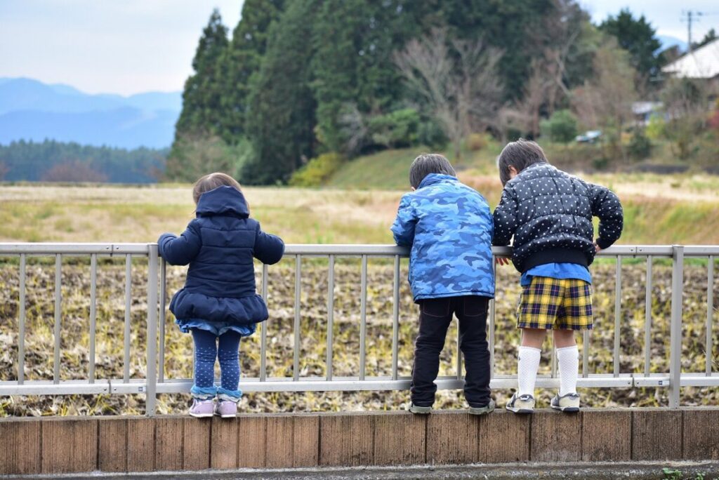 フェンス越しに畑を覗き込む三人の子供