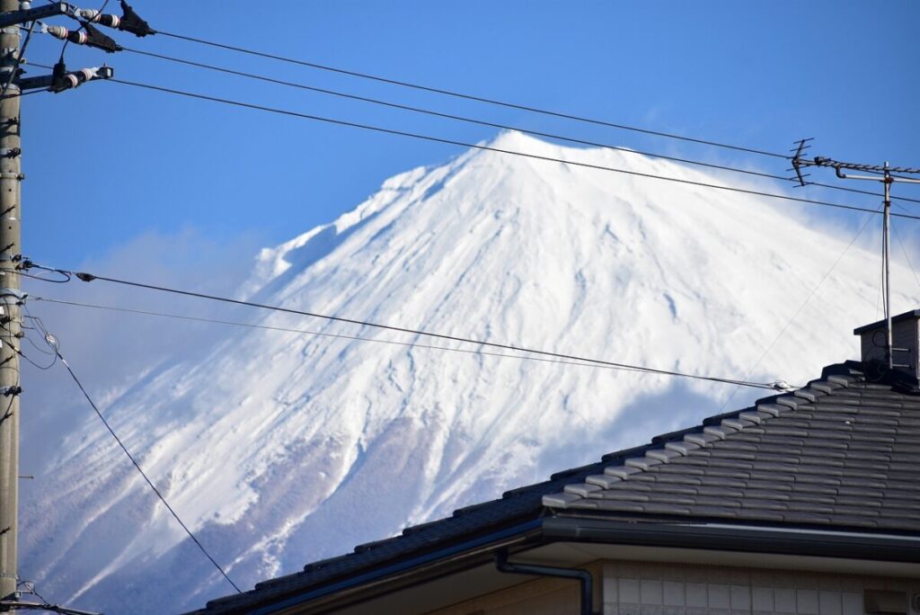 屋根の向こうに見える、冠雪した富士山と青空